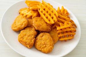 Fried chicken nuggets with fried potatoes on plate photo