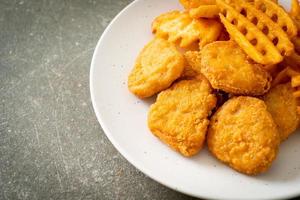 Fried chicken nuggets with fried potatoes on plate photo