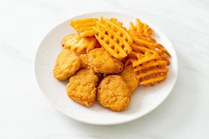 Fried chicken nuggets with fried potatoes on plate photo