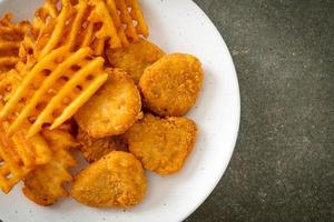 Fried chicken nuggets with fried potatoes on plate photo