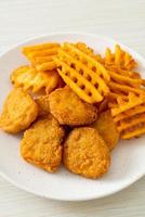 Fried chicken nuggets with fried potatoes on plate photo