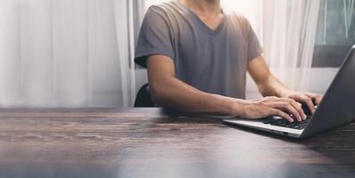 A man is typing on a laptop computer photo