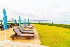 Chair pool or bed pool and umbrella around swimming pool with sea beach background at Pattaya in Thailand