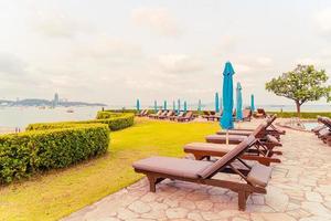 Chair pool or bed pool and umbrella around swimming pool with sea beach background at Pattaya in Thailand photo