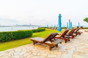 Chair pool or bed pool and umbrella around swimming pool with sea beach background at Pattaya in Thailand photo