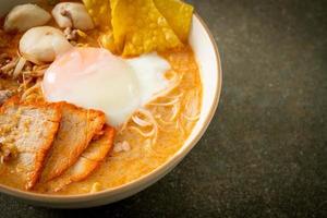 Rice vermicelli noodles with meatball, roasted pork and egg in spicy soup photo