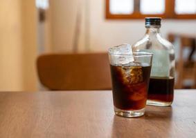 Vaso de café frío con cubitos de hielo en la mesa de madera foto