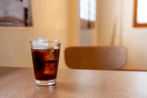 Vaso de café frío con cubitos de hielo en la mesa de madera foto