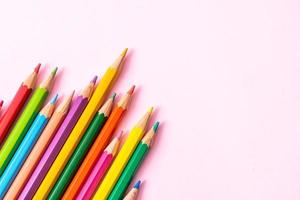 Colored pencils on pink background with copy space photo