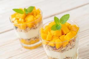 Fresh mango yogurt with granola in glass - healthy food style photo