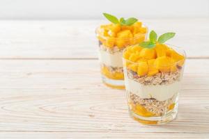 Yogur de mango fresco con granola en vidrio - estilo de comida saludable foto