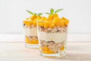 Fresh mango yogurt with granola in glass - healthy food style photo