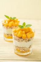 Fresh mango yogurt with granola in glass - healthy food style photo