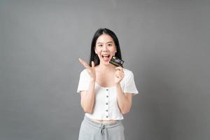 Mujer asiática con cara feliz y presentando tarjeta de crédito en mano mostrando confianza y seguridad para realizar el pago foto