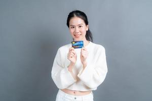 Portrait of a lovely young Asian woman in sweater showing credit card with copy space photo