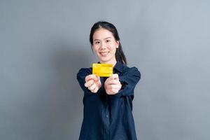 Portrait of a lovely young Asian woman showing credit card photo