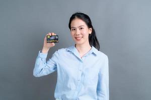 Portrait of a lovely young Asian woman showing credit card photo