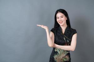 Hermosa joven asiática vistiendo traje tradicional chino con la mano que presenta en el lateral foto