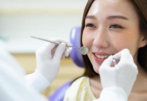Cierre la imagen del dentista que realiza el cuidado dental y compruebe si hay transportes dentales a la joven asiática en la clínica. concepto de salud y salud dental