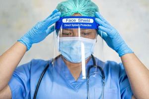 médico asiático con protector facial y traje de ppe nuevo normal para comprobar que el paciente protege la seguridad infección brote de coronavirus covid-19 en la sala de cuarentena del hospital de enfermería. foto