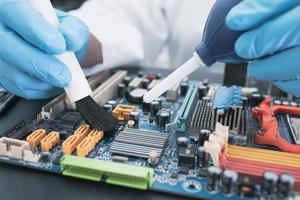 Technician use brush and air blower ball to clean dust in circuit board computer. Repair upgrade and maintenance technology. photo