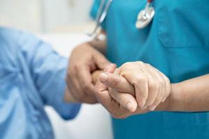 Doctor holding touching hands Asian senior or elderly old lady woman patient with love, care, helping, encourage and empathy at nursing hospital ward, healthy strong medical concept photo