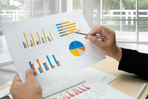 Asian accountant working and analyzing financial reports project accounting with chart graph and calculator in modern office, finance and business concept. photo