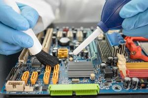 Technician use brush and air blower ball to clean dust in circuit board computer. Repair upgrade and maintenance technology. photo