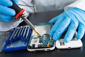 Technician repairing inside of mobile phone by soldering iron. Integrated Circuit. the concept of data, hardware, technology. photo