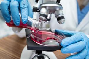 Asian scientist biochemist or microbiologist working research with a microscope in laboratory. For protect outbreak Coronavirus Covid19, bacteria and germs. photo