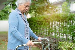 Asia anciana anciana o anciana usa andador con una salud fuerte mientras camina en el parque en felices vacaciones foto