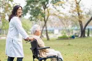 médico ayuda y cuidado paciente asiático mayor o anciano mujer sentada en silla de ruedas en el parque en la sala del hospital de enfermería, concepto médico fuerte y saludable. foto