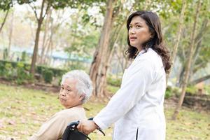 Doctor help and care Asian senior or elderly old lady woman patient sitting on wheelchair at park in nursing hospital ward, healthy strong medical concept. photo
