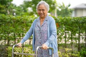 Asia anciana anciana o anciana usa andador con una salud fuerte mientras camina en el parque en felices vacaciones foto