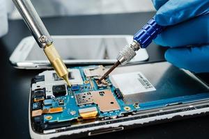 Technician repairing inside of hard disk by soldering iron. Integrated Circuit. The concept of data, hardware, technician and technology. photo