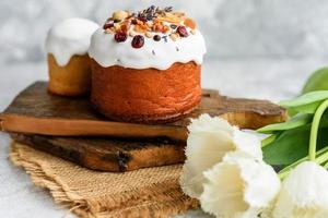 Festive cakes with white glaze, nuts and raisins with Easter eggs on the festive table photo