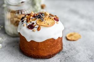 Festive cakes with white glaze, nuts and raisins with Easter eggs on the festive table photo