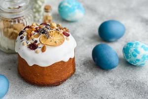 Pasteles festivos con glaseado blanco, nueces y pasas con huevos de pascua en la mesa festiva foto