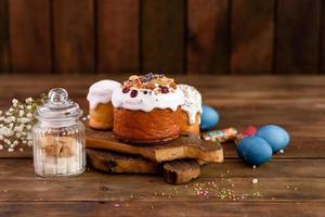 Festive cakes with white glaze, nuts and raisins with Easter eggs on the festive table photo