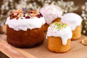 Festive cakes with white glaze, nuts and raisins with Easter eggs on the festive table photo