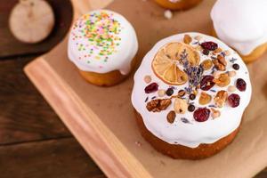 Festive cakes with white glaze, nuts and raisins with Easter eggs on the festive table photo