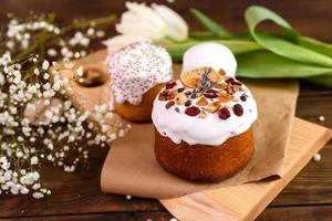 Festive cakes with white glaze, nuts and raisins with Easter eggs on the festive table photo