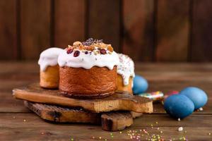 Festive cakes with white glaze, nuts and raisins with Easter eggs on the festive table photo