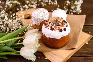 Festive cakes with white glaze, nuts and raisins with Easter eggs on the festive table photo