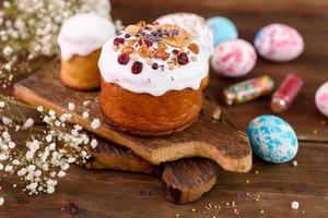 Festive cakes with white glaze, nuts and raisins with Easter eggs on the festive table photo