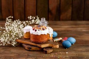 Festive cakes with white glaze, nuts and raisins with Easter eggs on the festive table photo