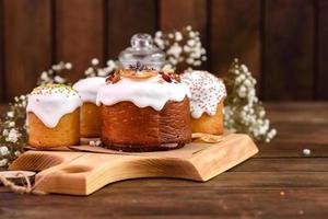 Festive cakes with white glaze, nuts and raisins with Easter eggs on the festive table photo