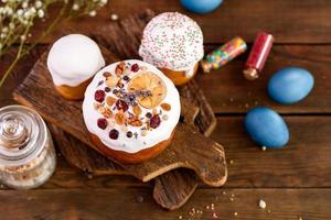 Festive cakes with white glaze, nuts and raisins with Easter eggs on the festive table photo