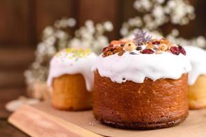 Festive cakes with white glaze, nuts and raisins with Easter eggs on the festive table photo