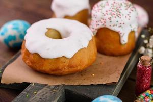 Festive cakes with white glaze, nuts and raisins with Easter eggs on the festive table photo